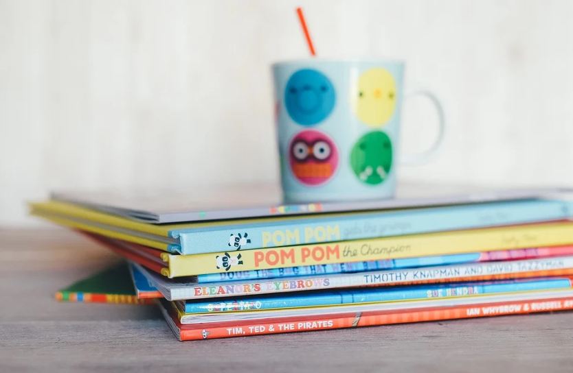 Children-Books-piled-with-a-smiley-faced-cup-placed-on-it