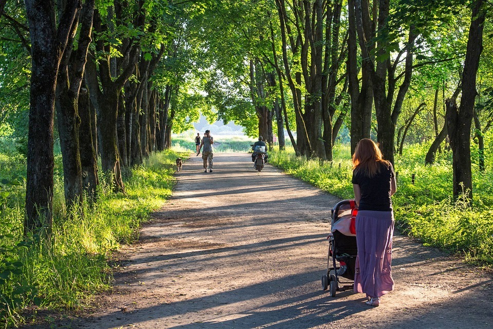 Image-of-a-woman-taking-her-kid-in-a-stroller-on-a-walk.
