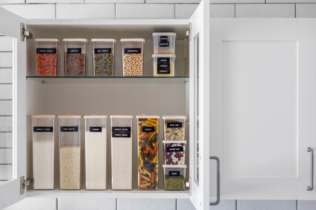 Kitchen storage organization uses plastic case. Placing and sorting food products into pp boxes. Keeping organizing a modern kitchen interior in Nordic style. General cleaning, tidying up at cuisine