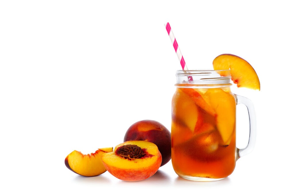 Summer peach iced tea in a mason jar glass with cut fruit
