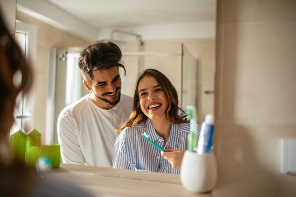 Woman brushing teeth with her spouse