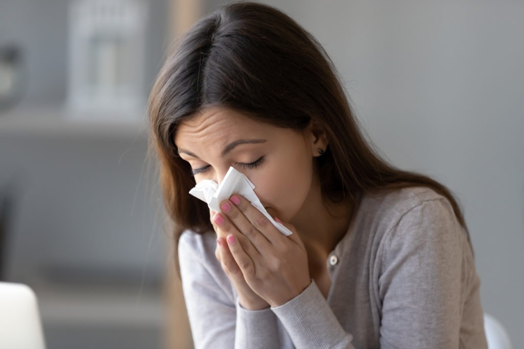 Woman holding tissue and blowing her nose