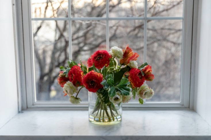a-flower-arrangement-in-a-glass-vase-in-front-of-the-window
