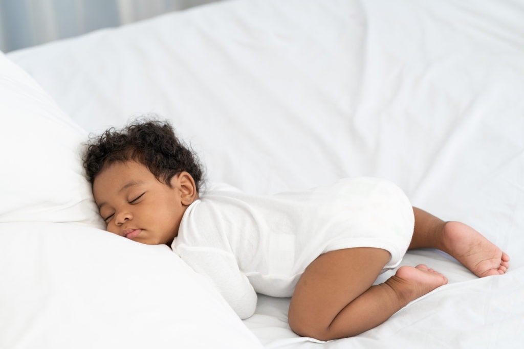 black african american baby sleeping on a white mattress
