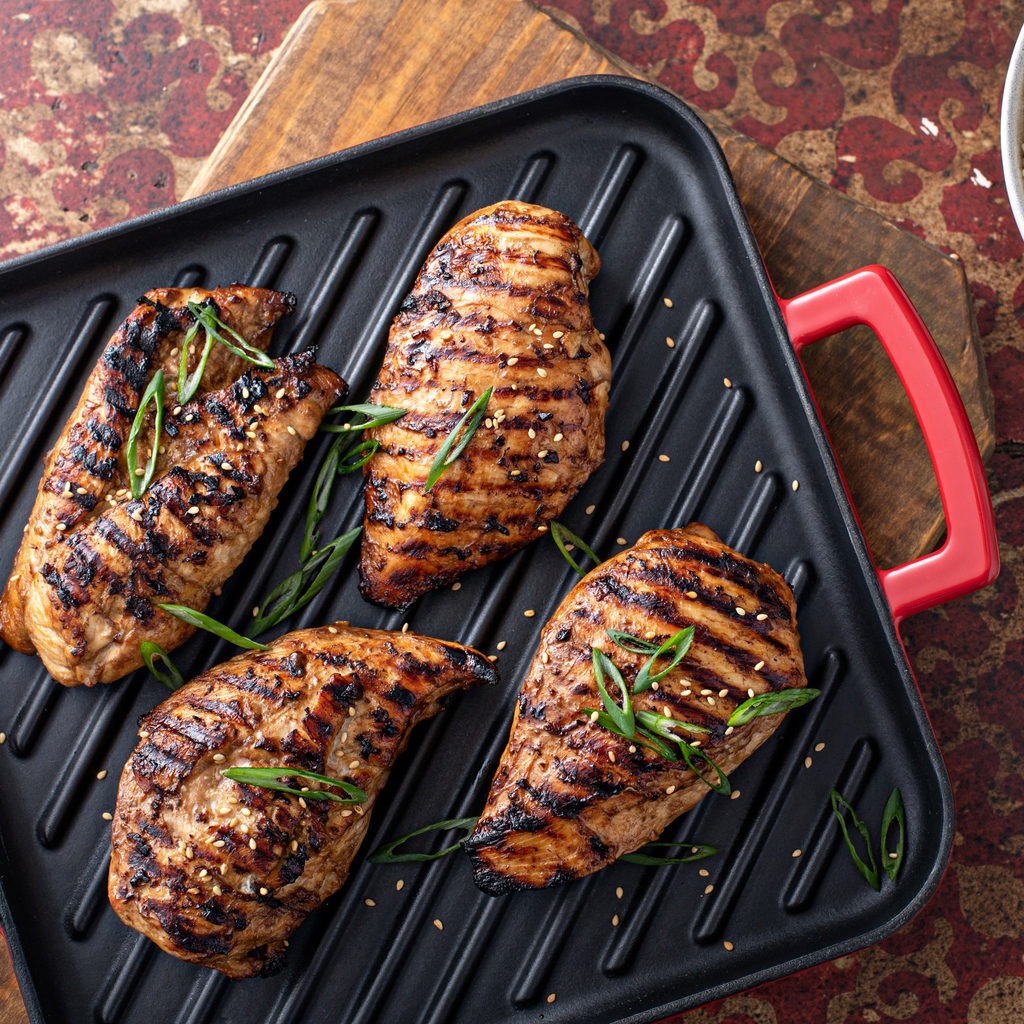 Grilled teriyaki chicken breast on a grill pan with green onions