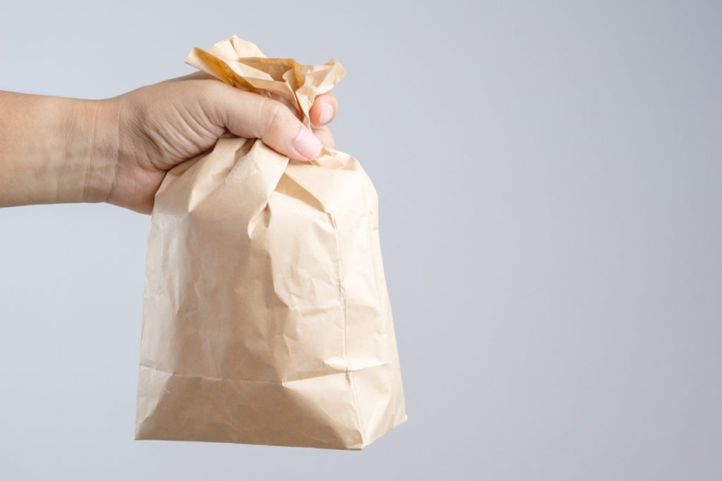 Hand holding crumble brown paper bag
