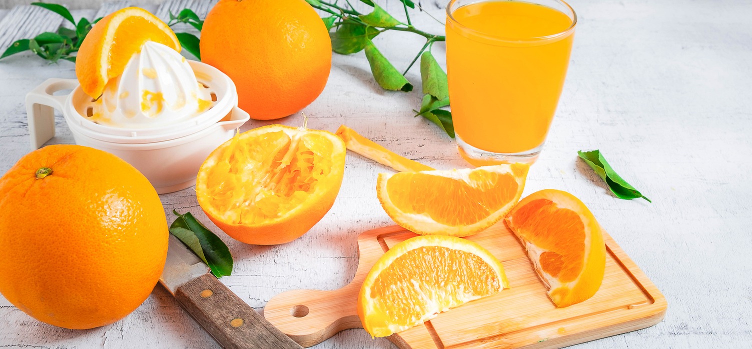 Homemade squeezed orange juice and fresh oranges fruits on a white wooden background. Cut the orange fruit in half to make orange juice