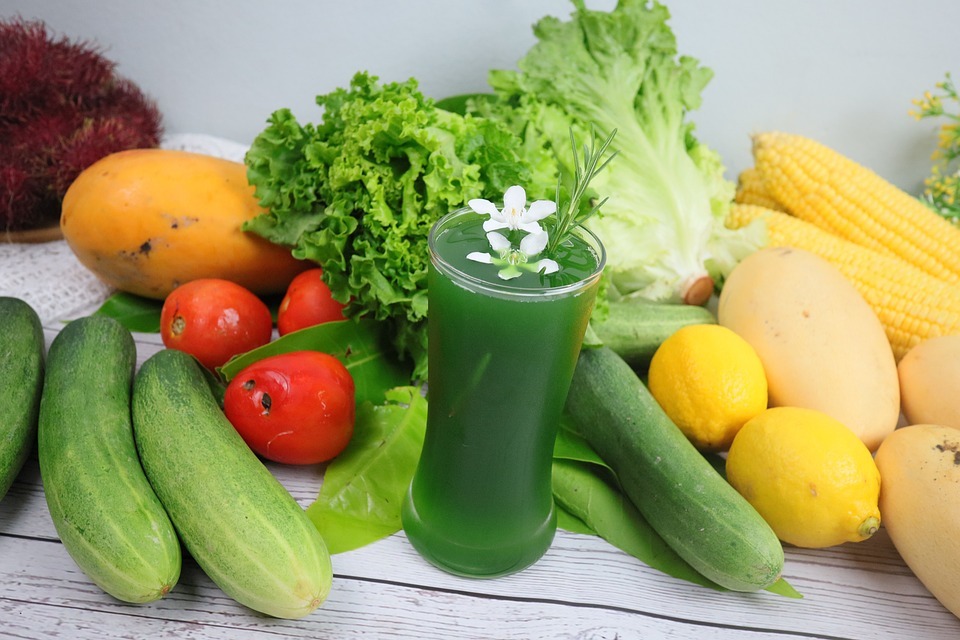 Lettuce juice in a drinking glass with a variety of vegetables around it