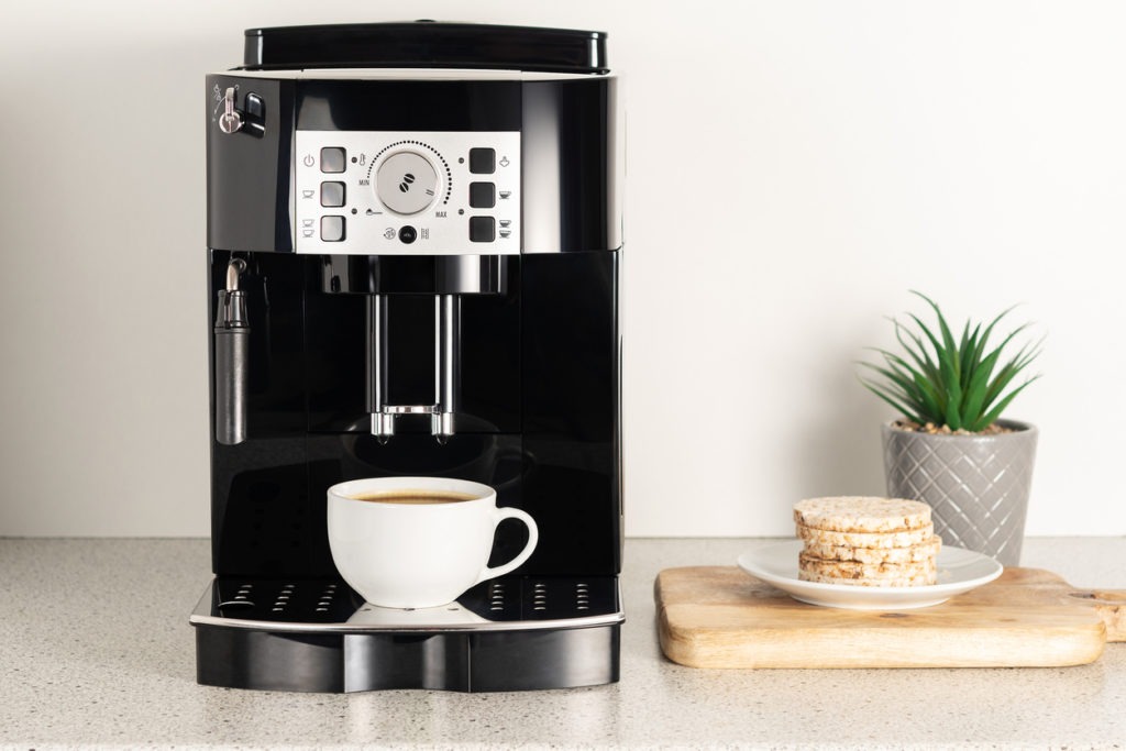 Modern espresso coffee machine with a cup in interior of kitchen closeup