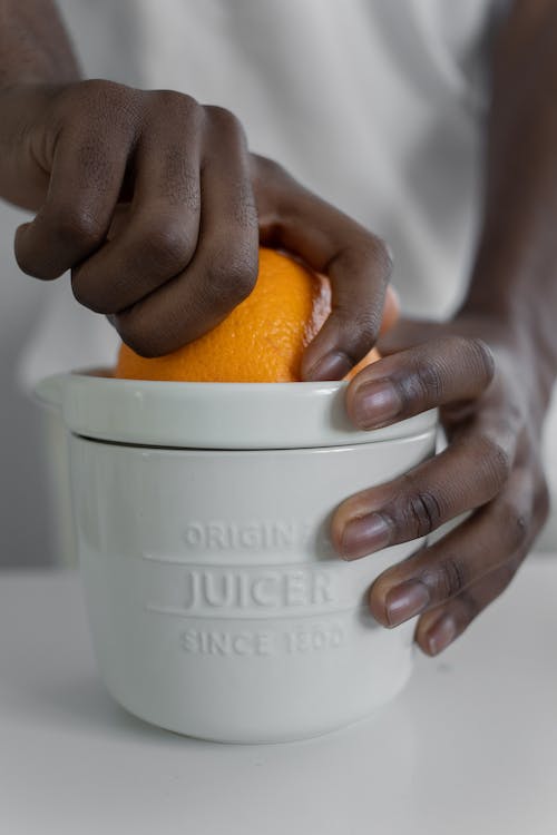 A person squeezing orange juice in a juicer
