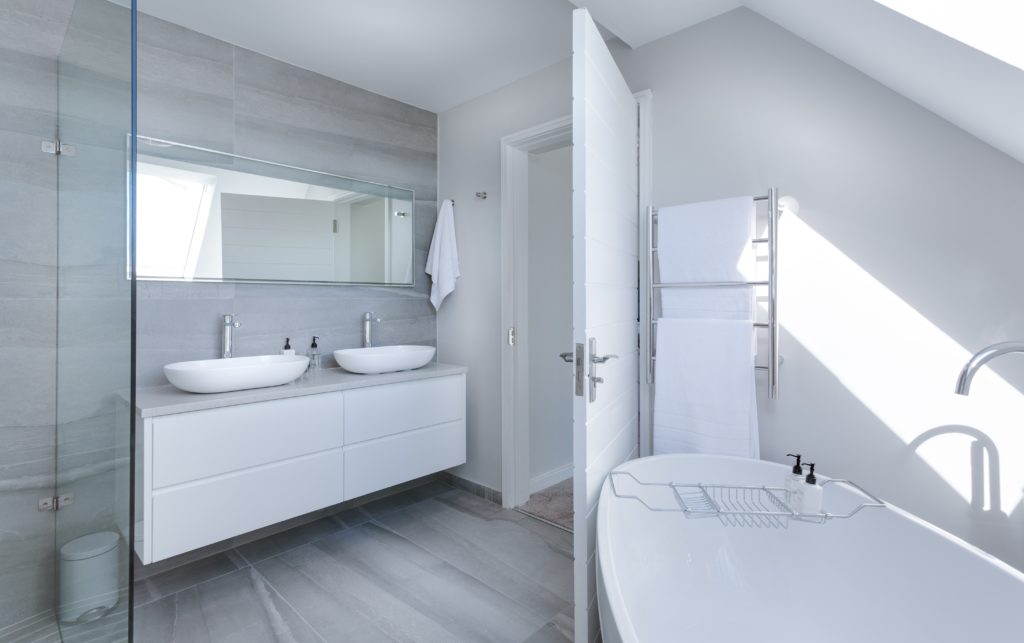 white-bathroom-interior-bathtub-two-sinks-towels-on-a-rack-scaled