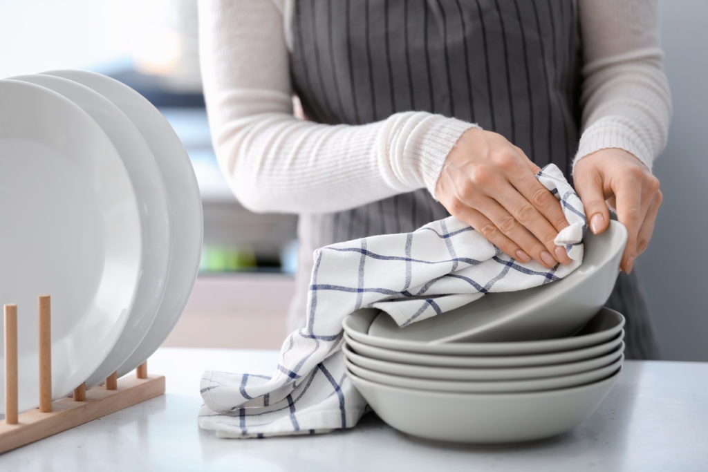 Woman wiping plate with towel in kitchen