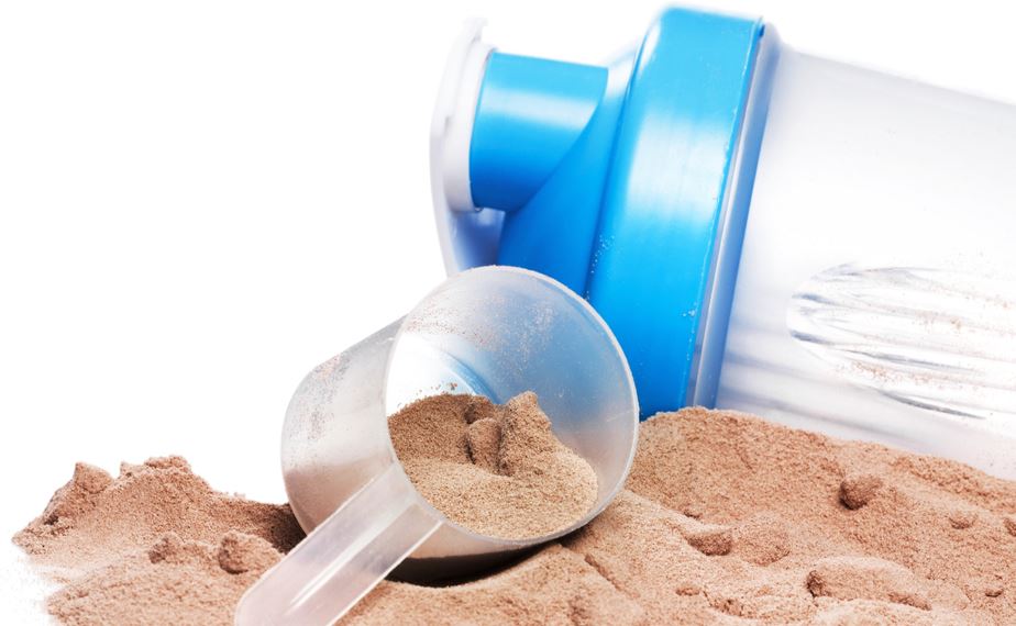 A bottle blender lying down on a flat surface with scoop and chocolate whey protein