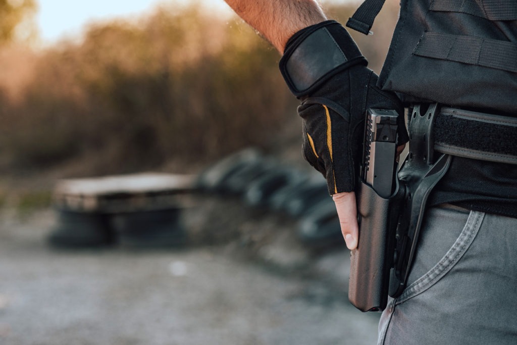 A close-up image of a man holding a gun in a holster