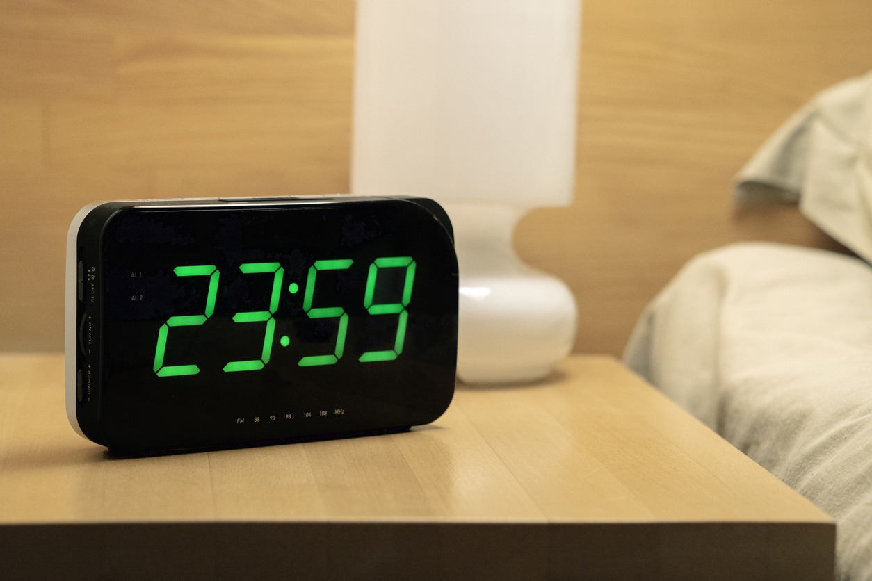 A digital clock on a bedside table