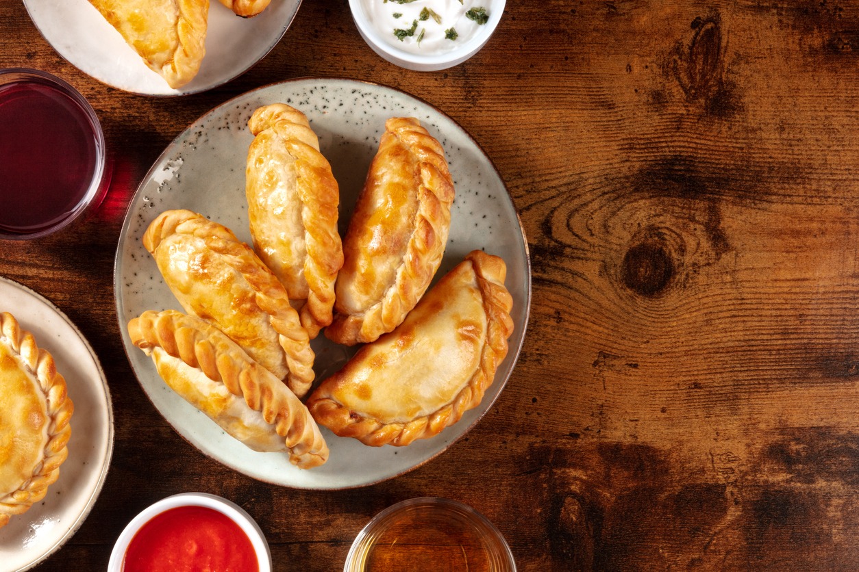 A dinner of empanadas taken from above against a background of dark, rustic wood