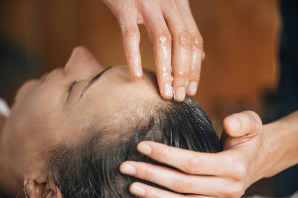 A woman taking pleasure in an Ayurvedic oil hair treatment.