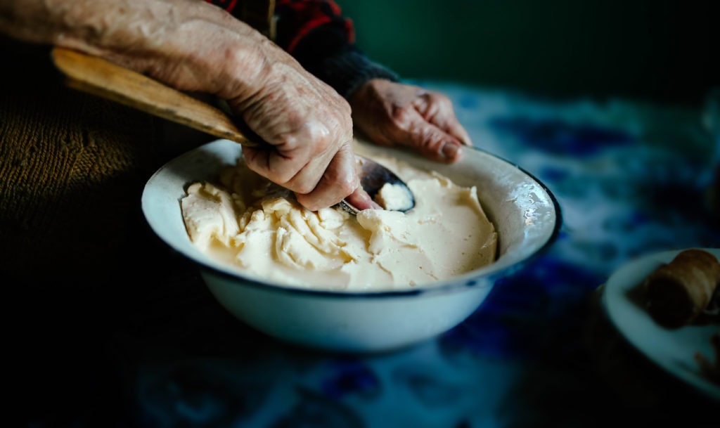 An old woman making homemade butter