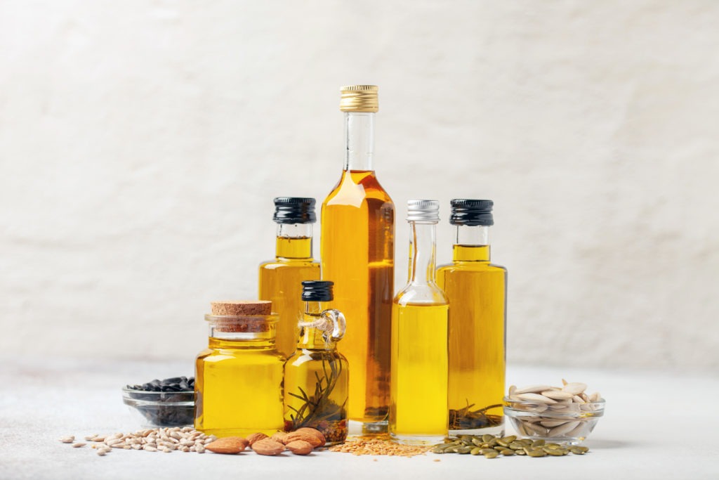 Bottles of various vegetable and nut oils against a vivid background. 