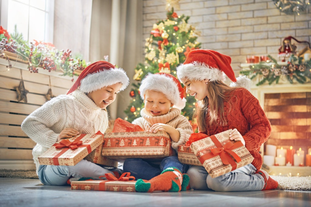 Children-opening-their-Christmas-gifts-with-Christmas-tree-in-the-background