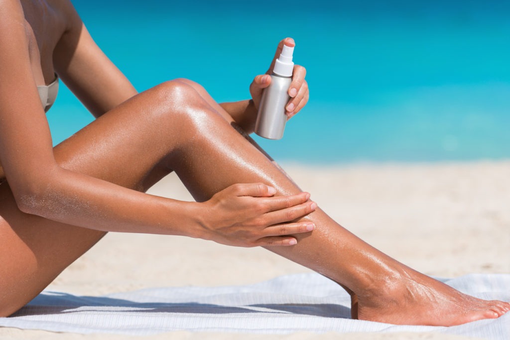 During her beach sunbathing, a woman is massaging sunscreen. 