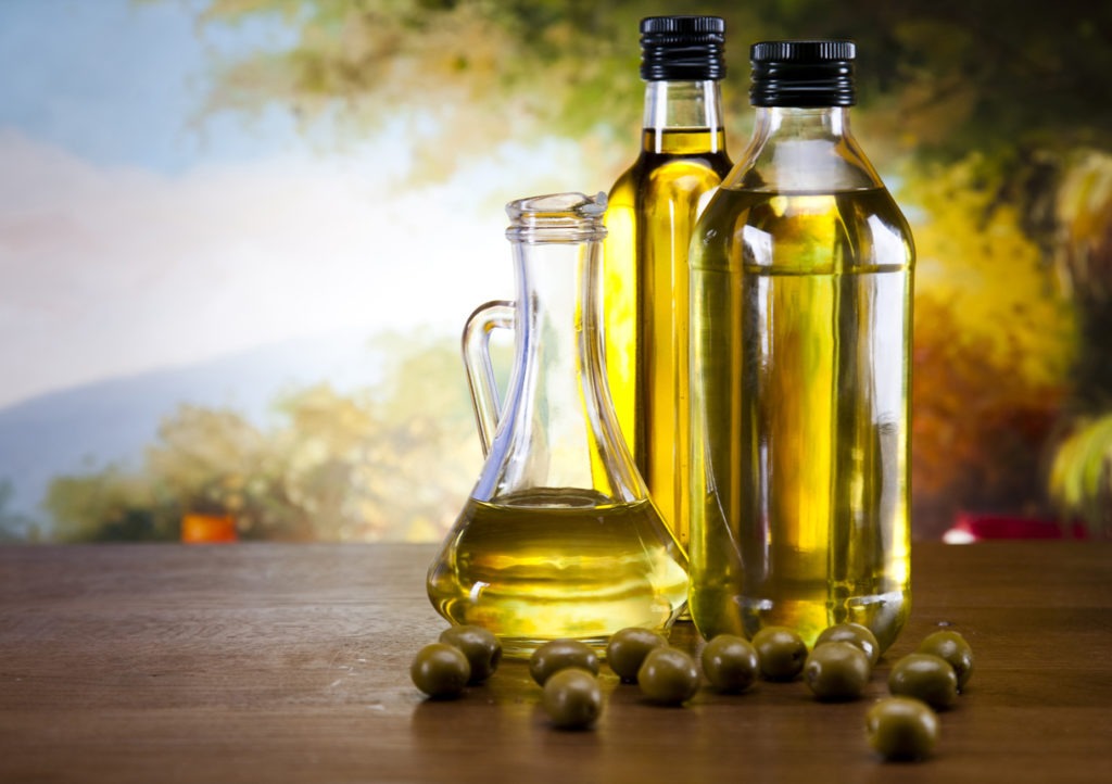 EVOO in bottles and fresh olives on top of the table. 