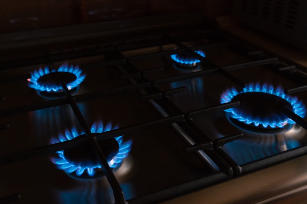 Four burners with blue flames equidistant to one another