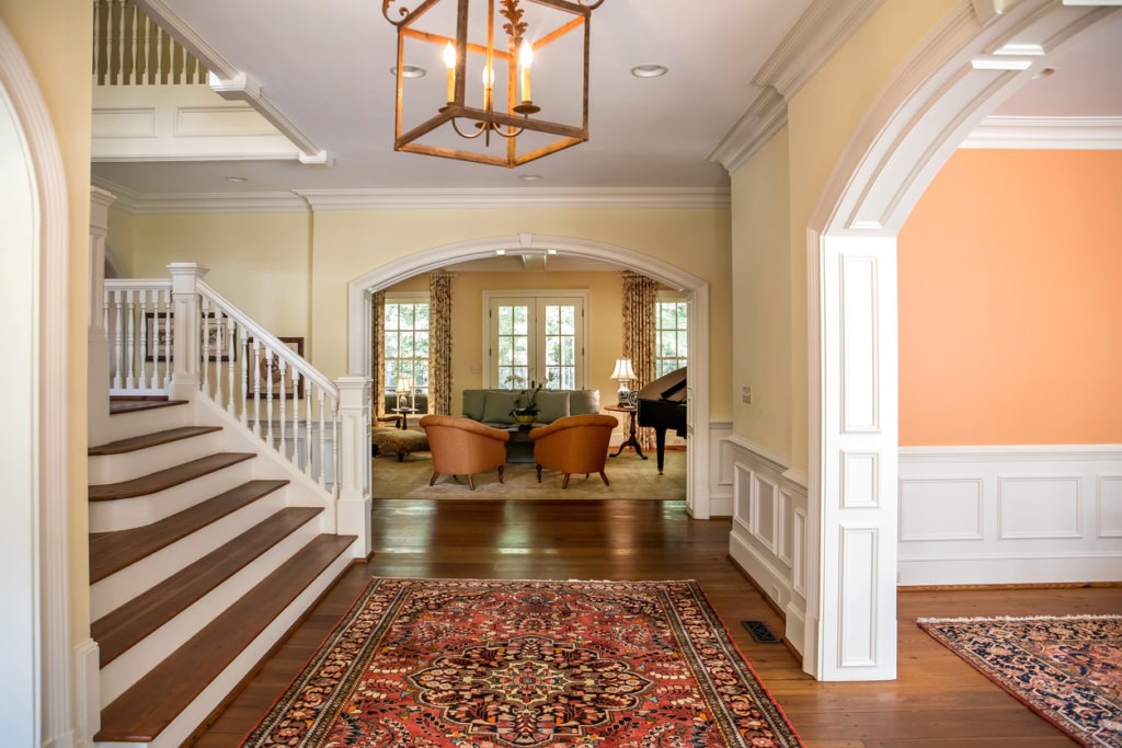 Grand and elegant yellow entrance to a home with stairs and oriental rug 