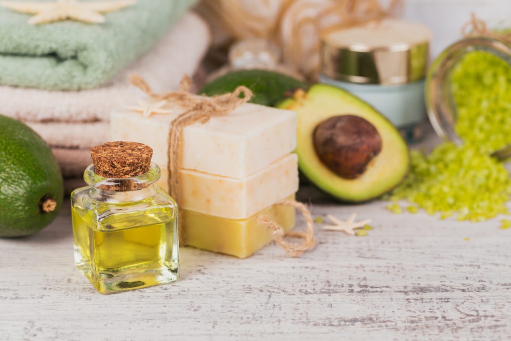 Natural handcrafted soap and cosmetic oil with avocado on a background of white rustic wood. 