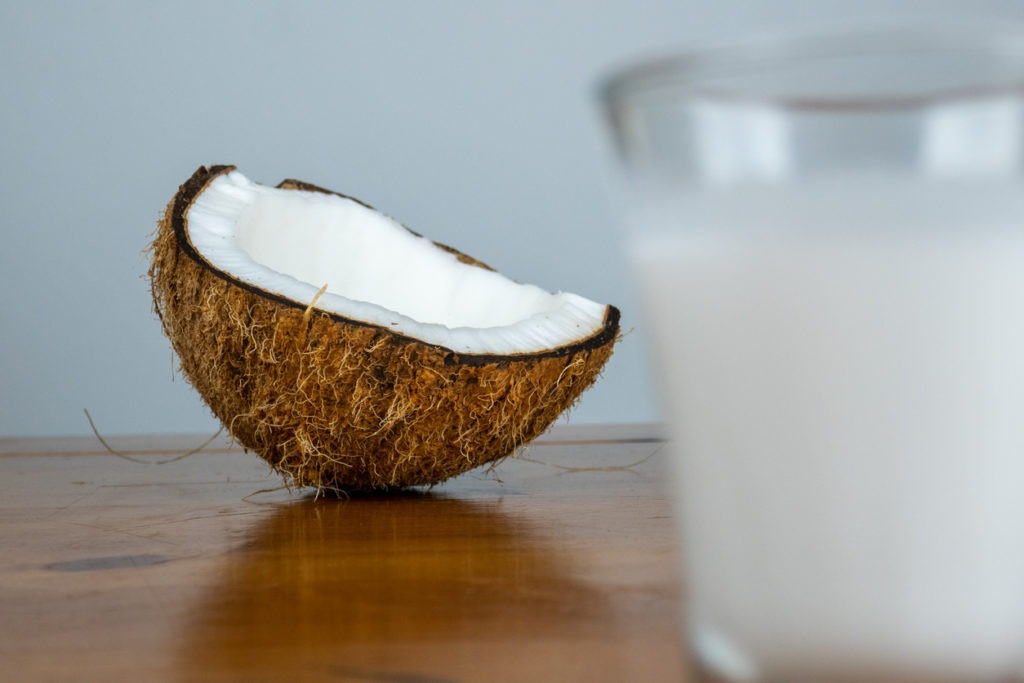 On a light colored background, brown dry coconut is served on a wooden table.
