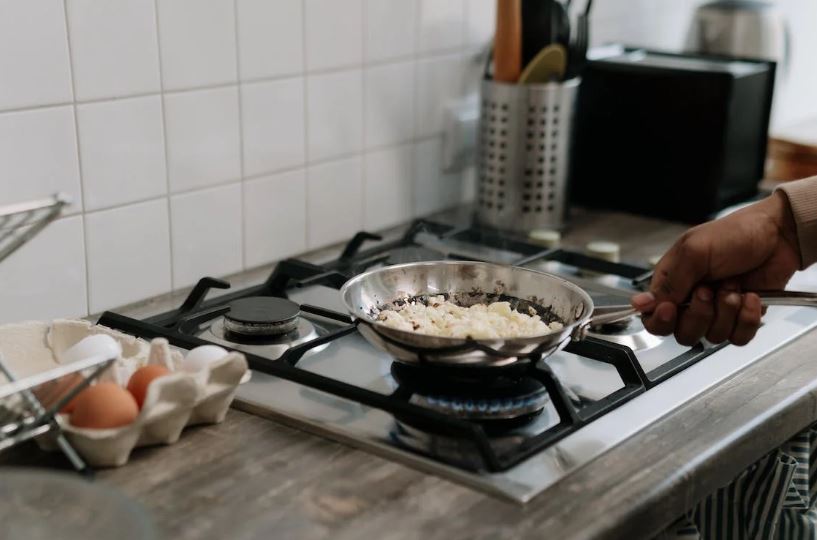 Person holding a pan on the stove 