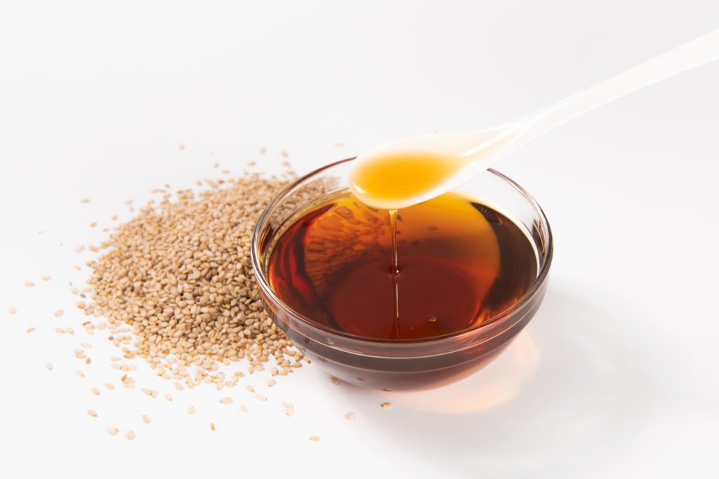 Sesame oil and seeds against a white background. 