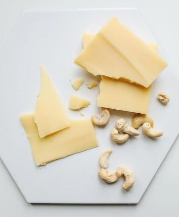 Sliced cheese beside cashew nuts