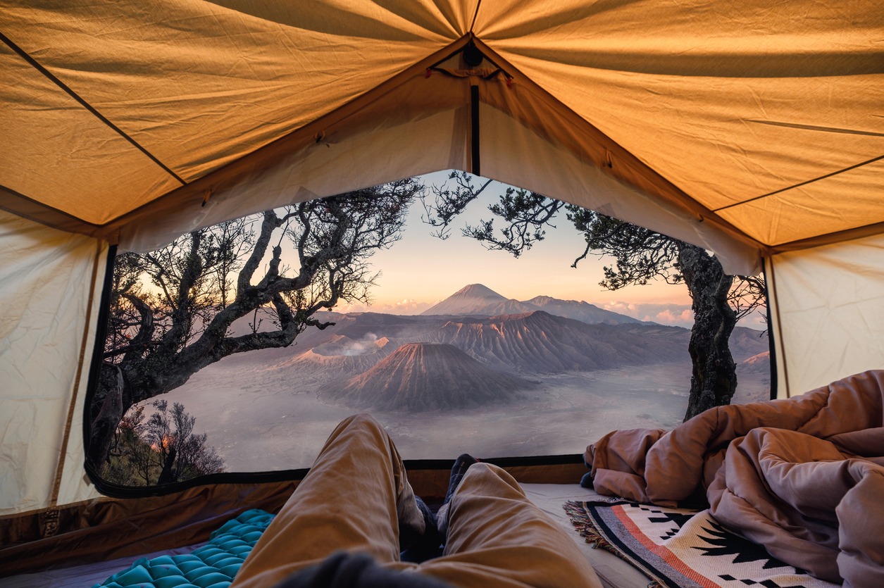 Traveler man relaxing and taking the view of Bromo active volcano inside a tent