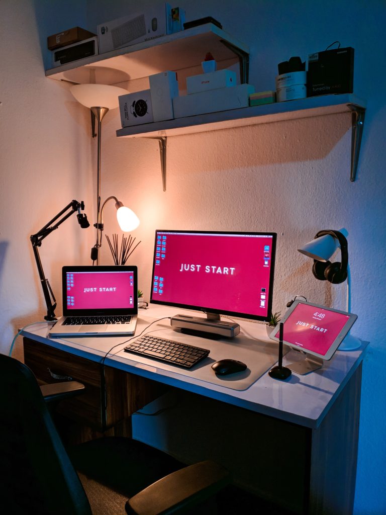 a-computer-monitor-a-laptop-and-a-lamp-on-a-table-scaled