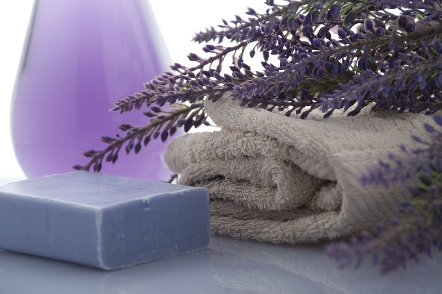 a-lavender-soap-with-lavender-flowers-and-a-folded-towel-in-the-background.