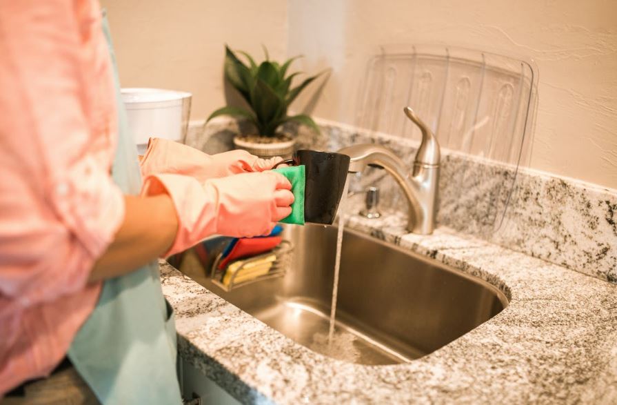 a woman washing dishes with protective gloves