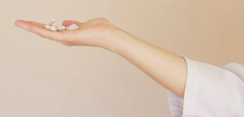 a woman’s palm with a bunch of white pills