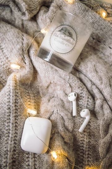 candle in a glass, knitted sweater with air pods and air pods case