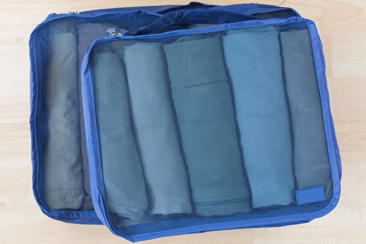 Cube meshed bags with rolled clothes. Set of travel organizer to help packing well organized