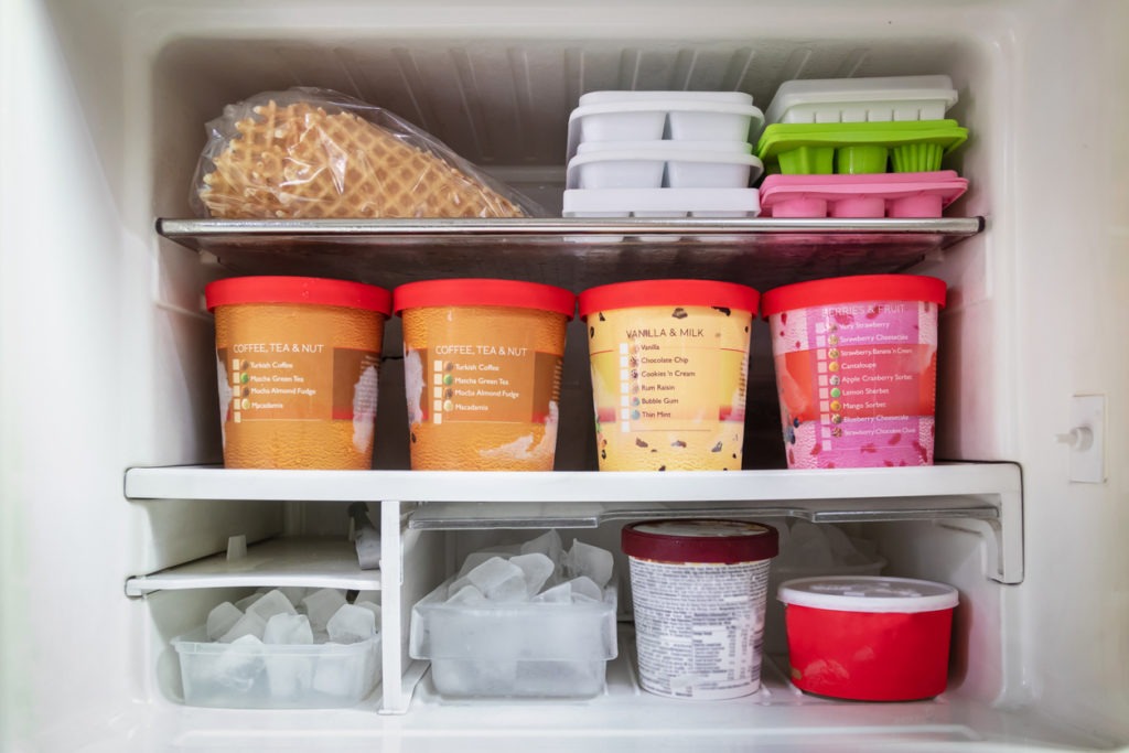 full of bucket container ice creams flavor and ice cubes inside the freezer
