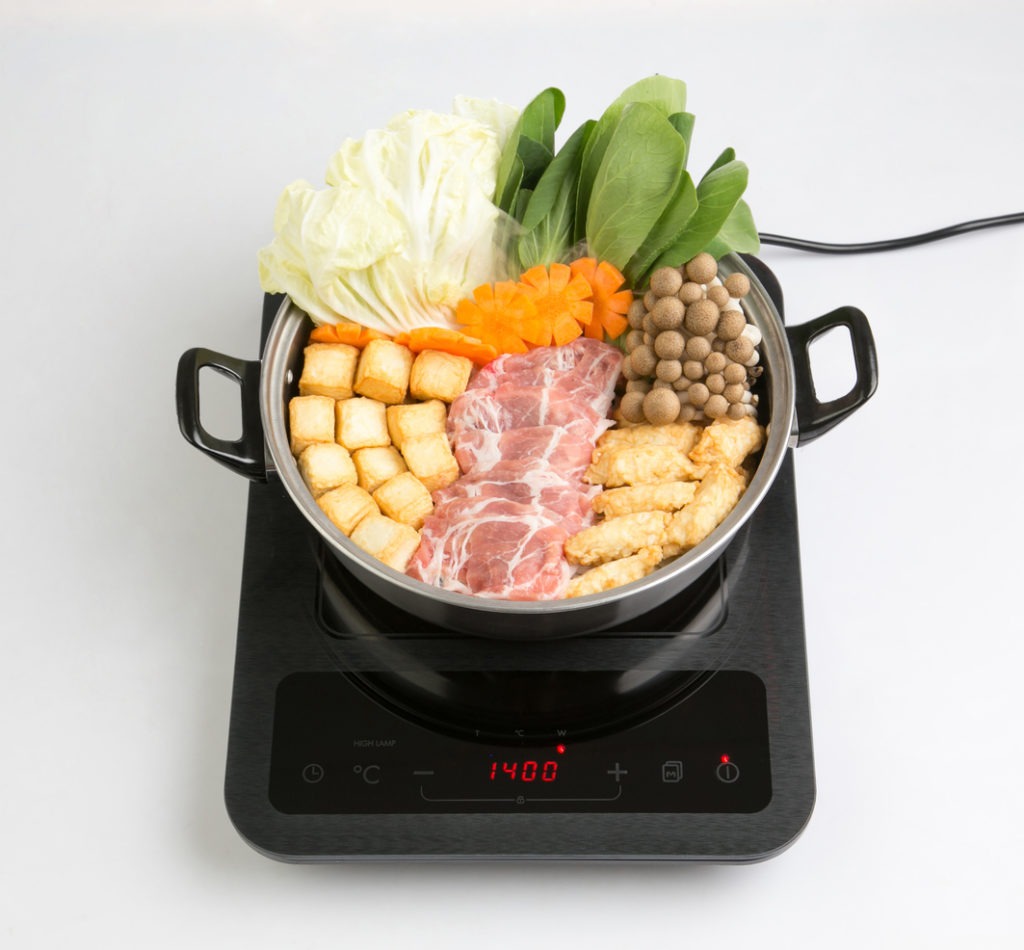 Induction cooktop with sukiyaki pot isolated on white background