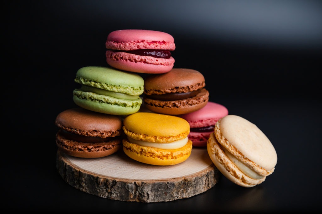 Macarons cookie dessert from France in a stack on wooden board and black background
