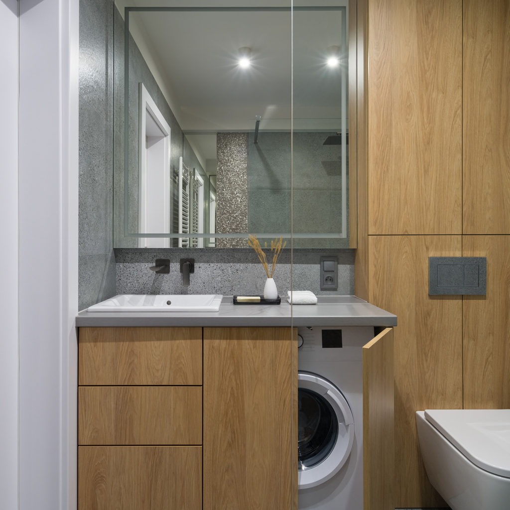 Modern bathroom with washing machine in cabinet