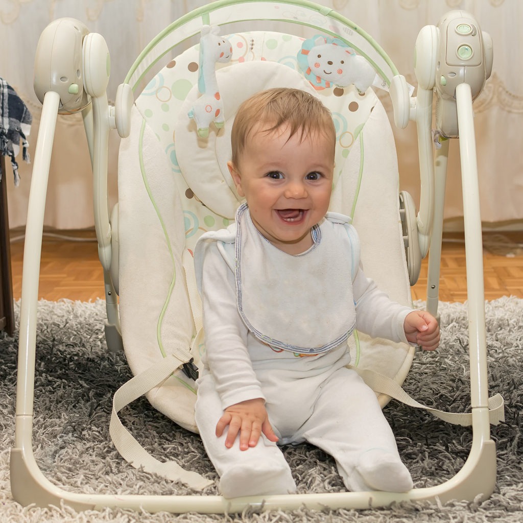 A smiling baby sitting in a baby chair