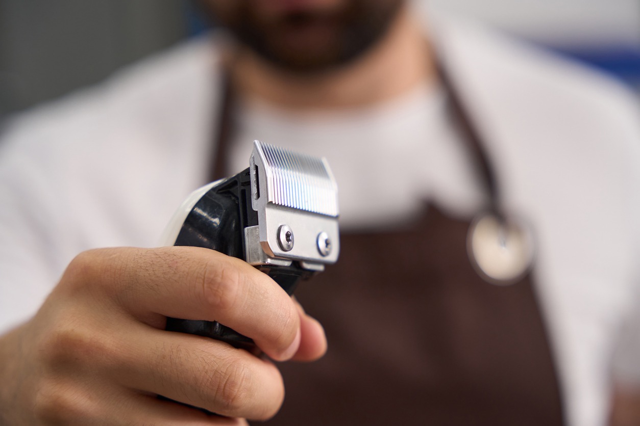 A barber holding electric hair trimmers
