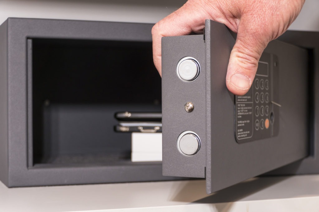 A hand opening a hotel room safe
