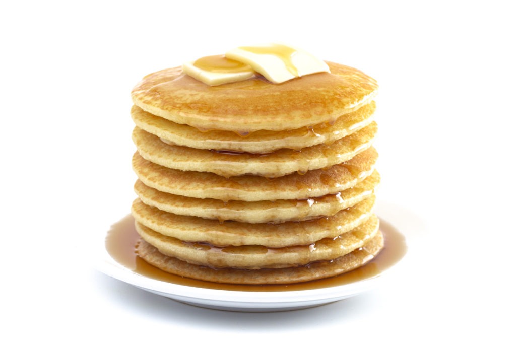 A stack of buttermilk pancakes with butter and syrup on top