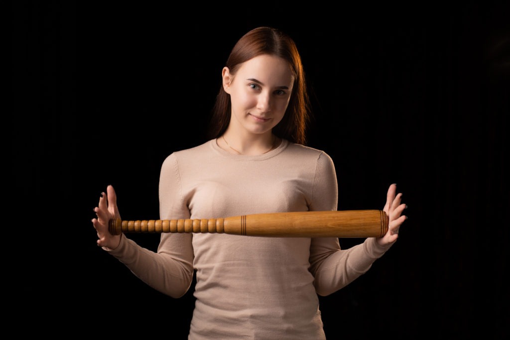 A young woman holds a bat in her hands