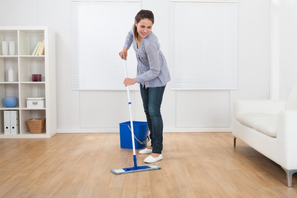 Barefoot woman cleaning the floor with a microfiber flat mop
